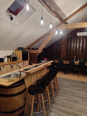 Une cuisine avec un bar en bois, des tabourets et des luminaires suspendus.