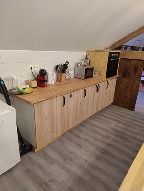 Ett modernt kök med träskåp, en mikrovågsugn och en kaffebryggare.