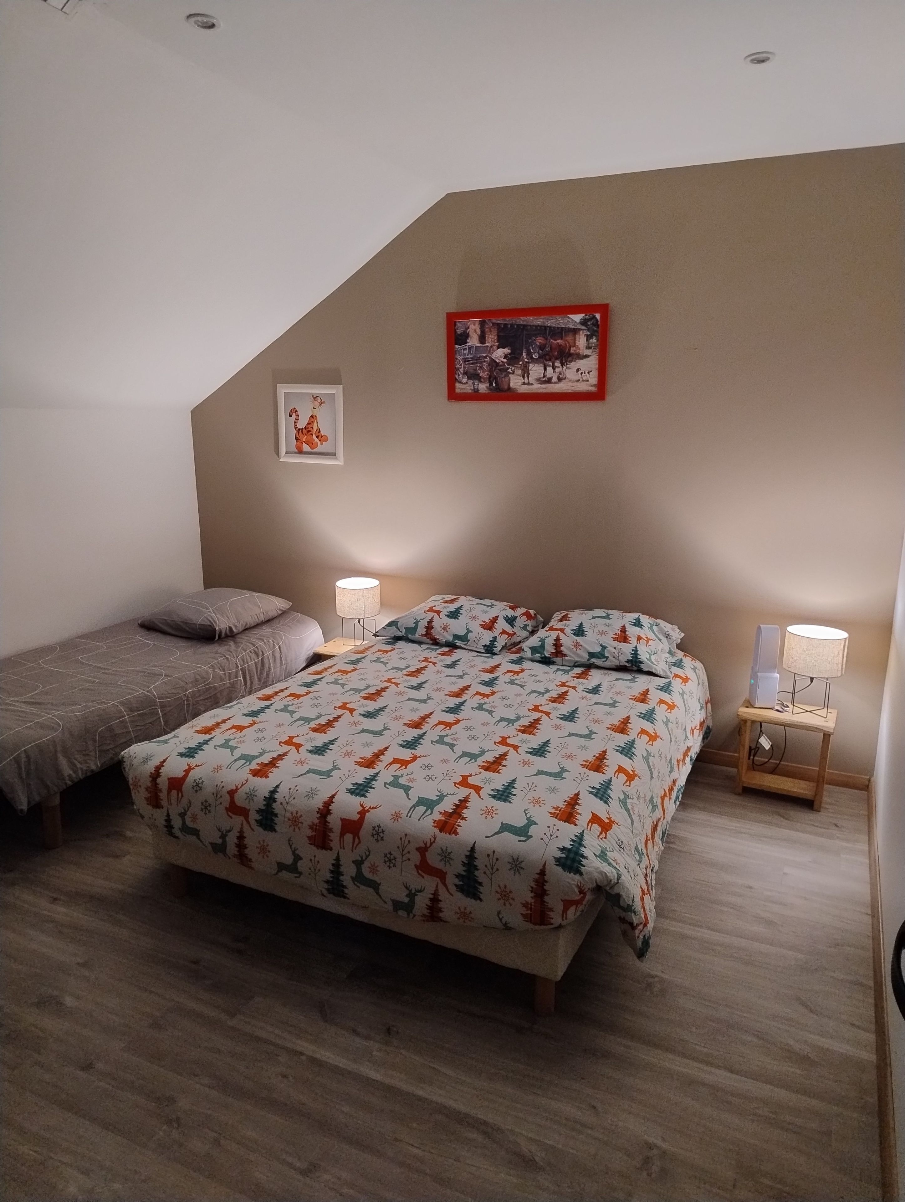 Een slaapkamer met een bed, een nachtkastje, een lamp en een aan de muur hangend schilderij.