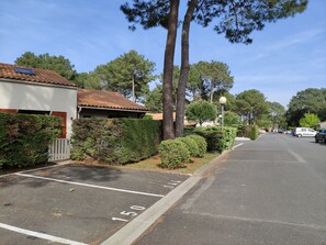 A parking lot with marked spaces, a building with a tiled roof, and surrounding trees. - New Listing (Les Mathes)