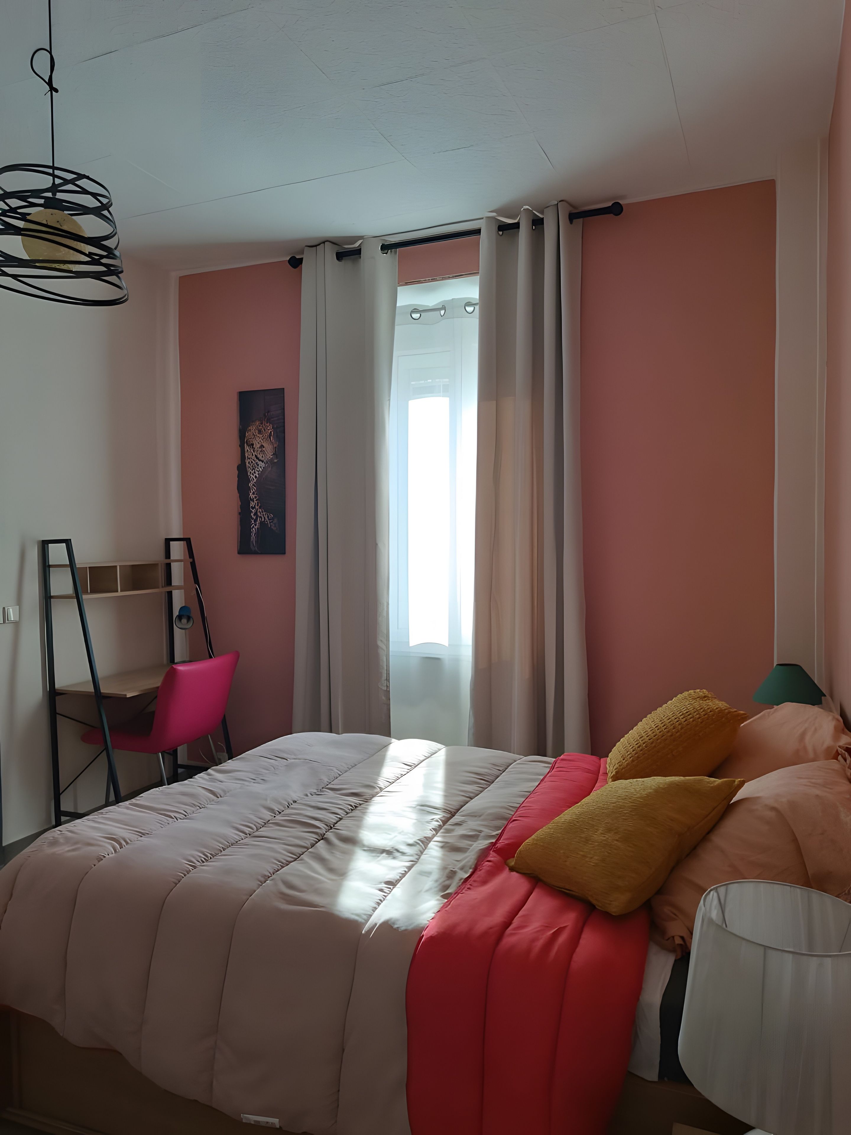 Une chambre à coucher avec un lit, un bureau, une chaise et une fenêtre avec des rideaux.