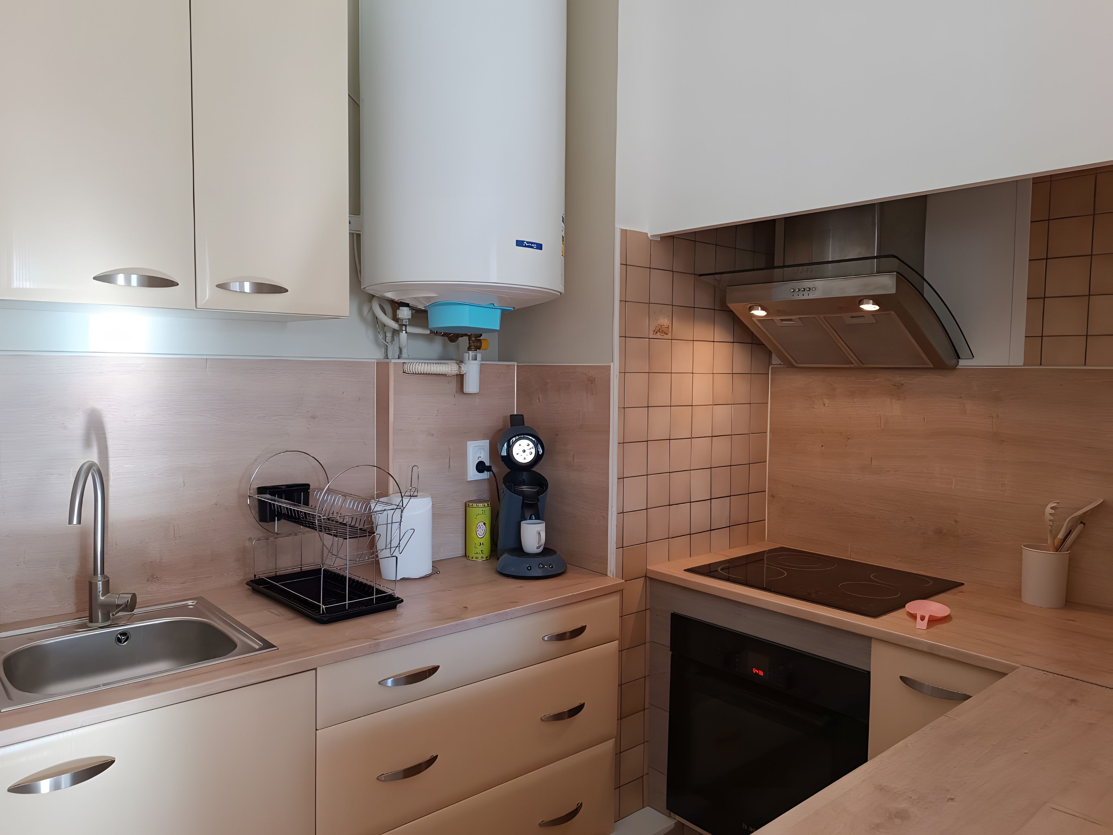 A modern kitchen with a built-in dishwasher, a coffee machine, and a kettle.