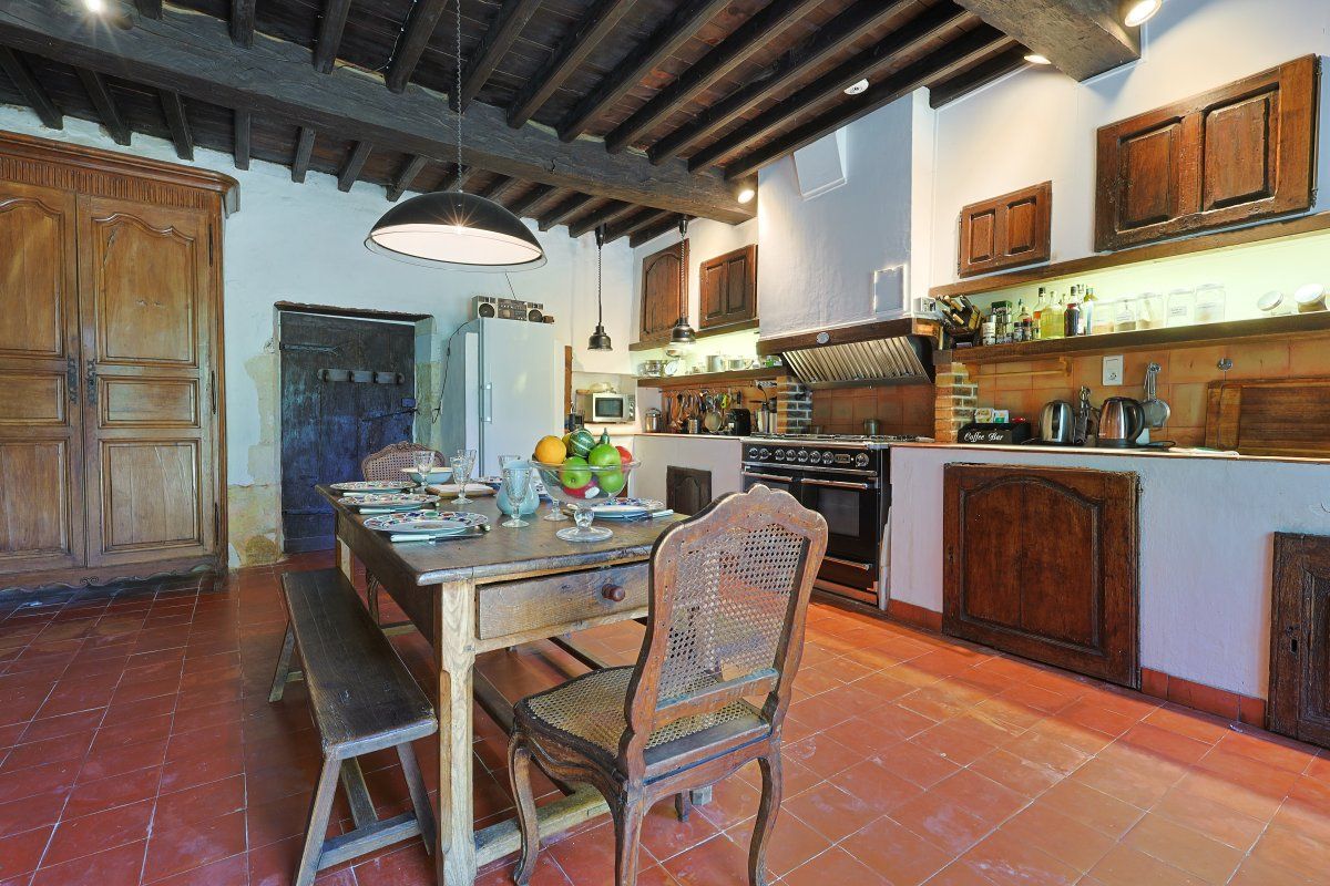 A rustic kitchen with wooden cabinets, a large island, and a dining table with benches.