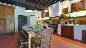 A rustic kitchen with wooden cabinets, a large island, and a dining table with benches.