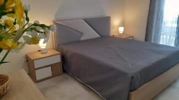 Una camera da letto con un letto, comodini, una lampada e un vaso con fiori.