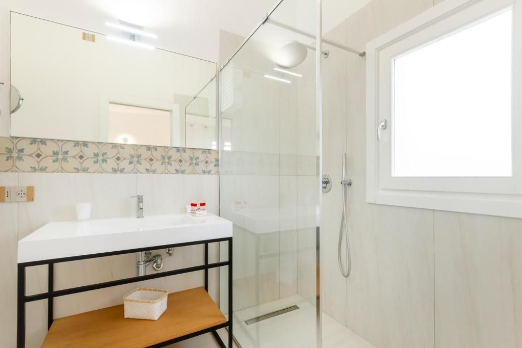 Une salle de bain moderne avec une douche à parois de verre, un lavabo blanc et une étagère en bois.