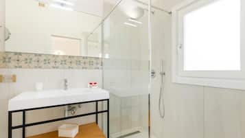 Une salle de bain moderne avec une douche à parois de verre, un lavabo blanc et une étagère en bois.