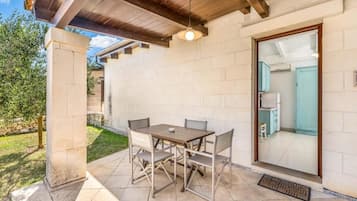 Patio esterno con tavolo e sedie, ventilatore a soffitto e vista su una cucina.