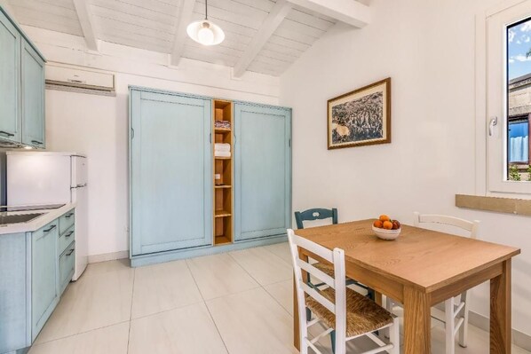A kitchen with a white refrigerator, a blue cabinet, and a dining table with chairs.