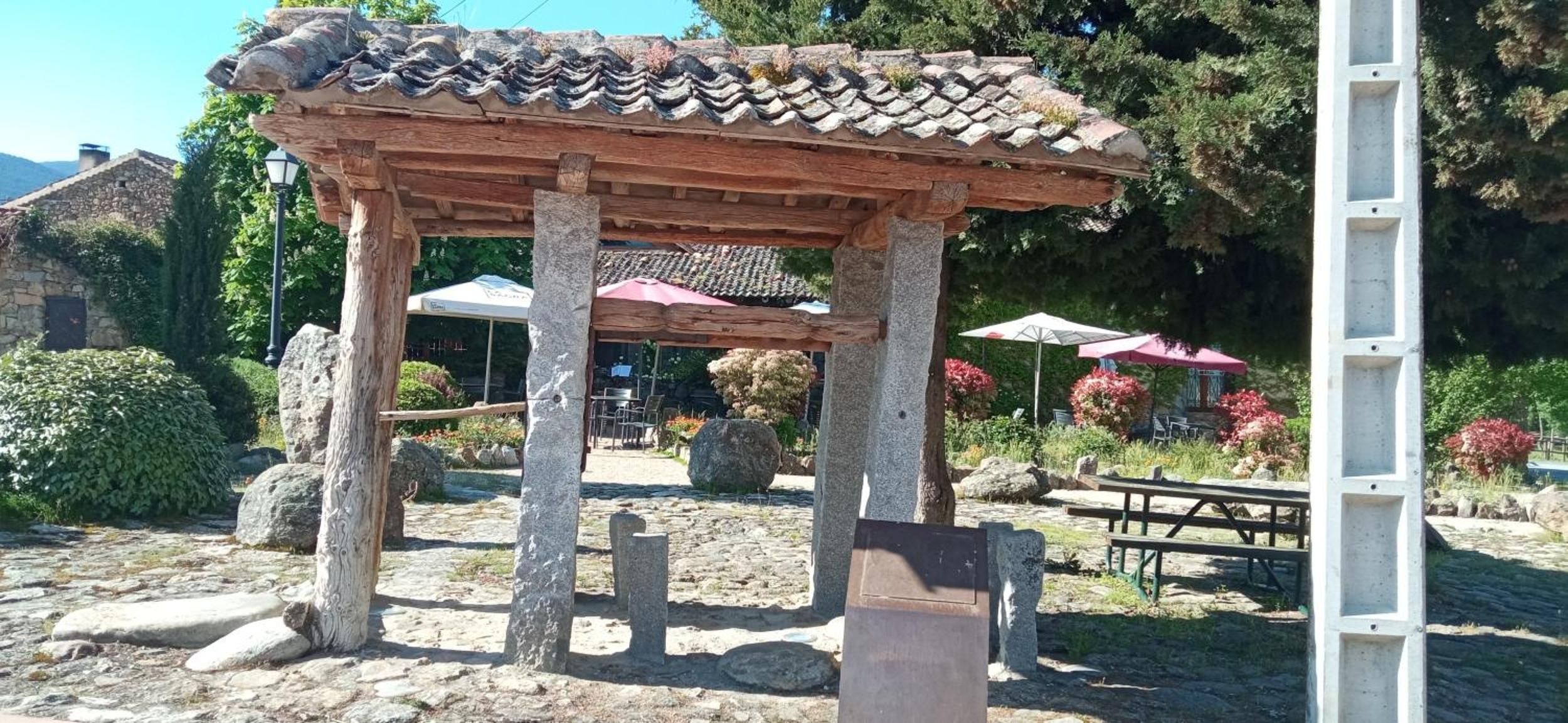 Ein traditioneller, hölzerner Pavillon mit Ziegeldach, umgeben von Steinen und Pflanzen.