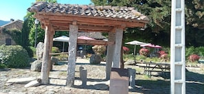Ein traditioneller, hölzerner Pavillon mit Ziegeldach, umgeben von Steinen und Pflanzen.
