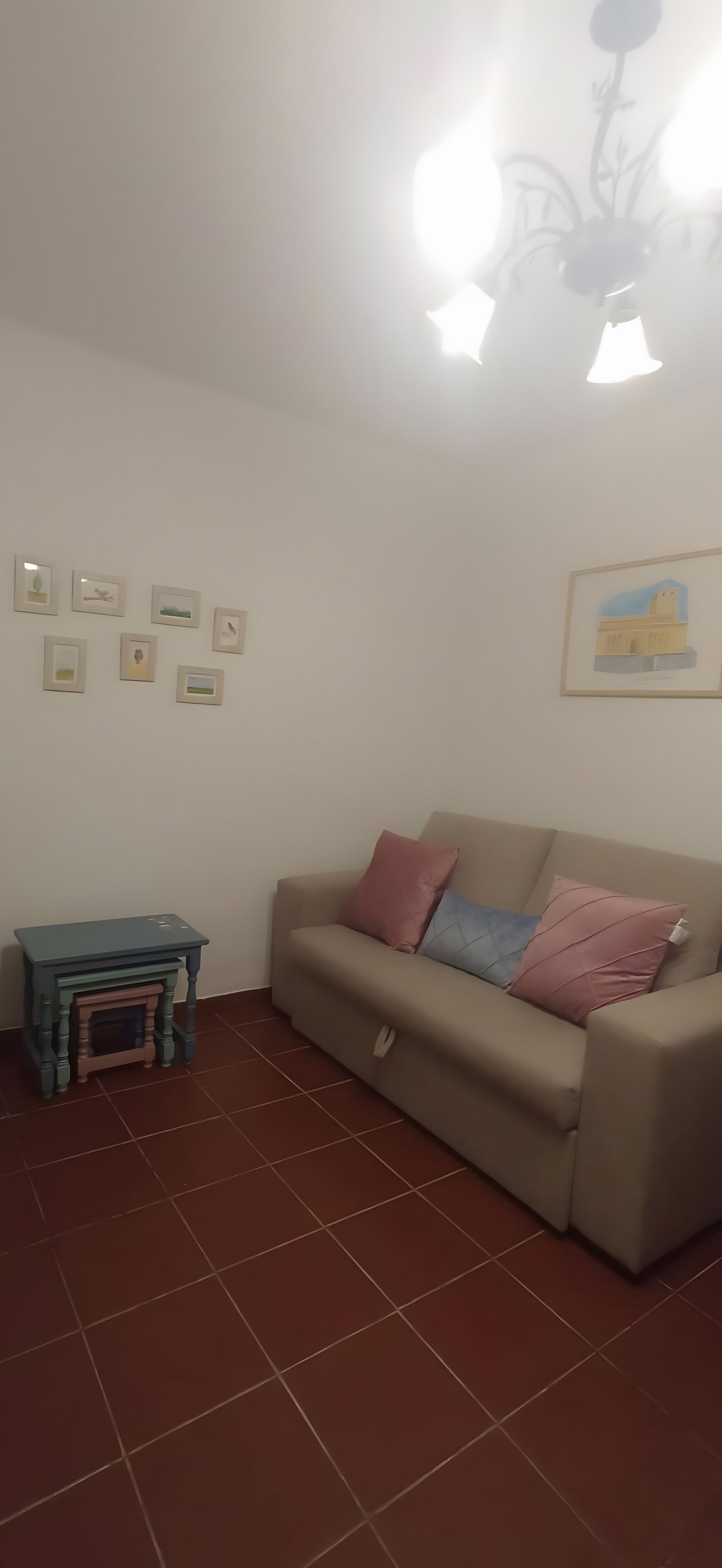 Una sala de estar con un sofá, una mesita y varias fotografías enmarcadas en la pared.