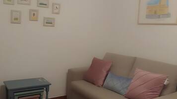 Una sala de estar con un sofá, una mesita y varias fotografías enmarcadas en la pared.