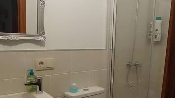 Een badkamer met toilet, wastafel en douche.