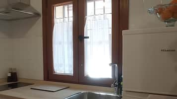 Una cocina con un lavaplatos de acero inoxidable, lavavajillas y refrigerador.