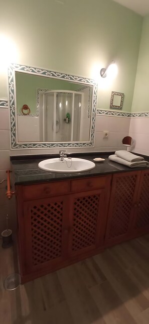 Ein Badezimmer mit einem großen Spiegel, einem Waschbecken und einer Dusche.