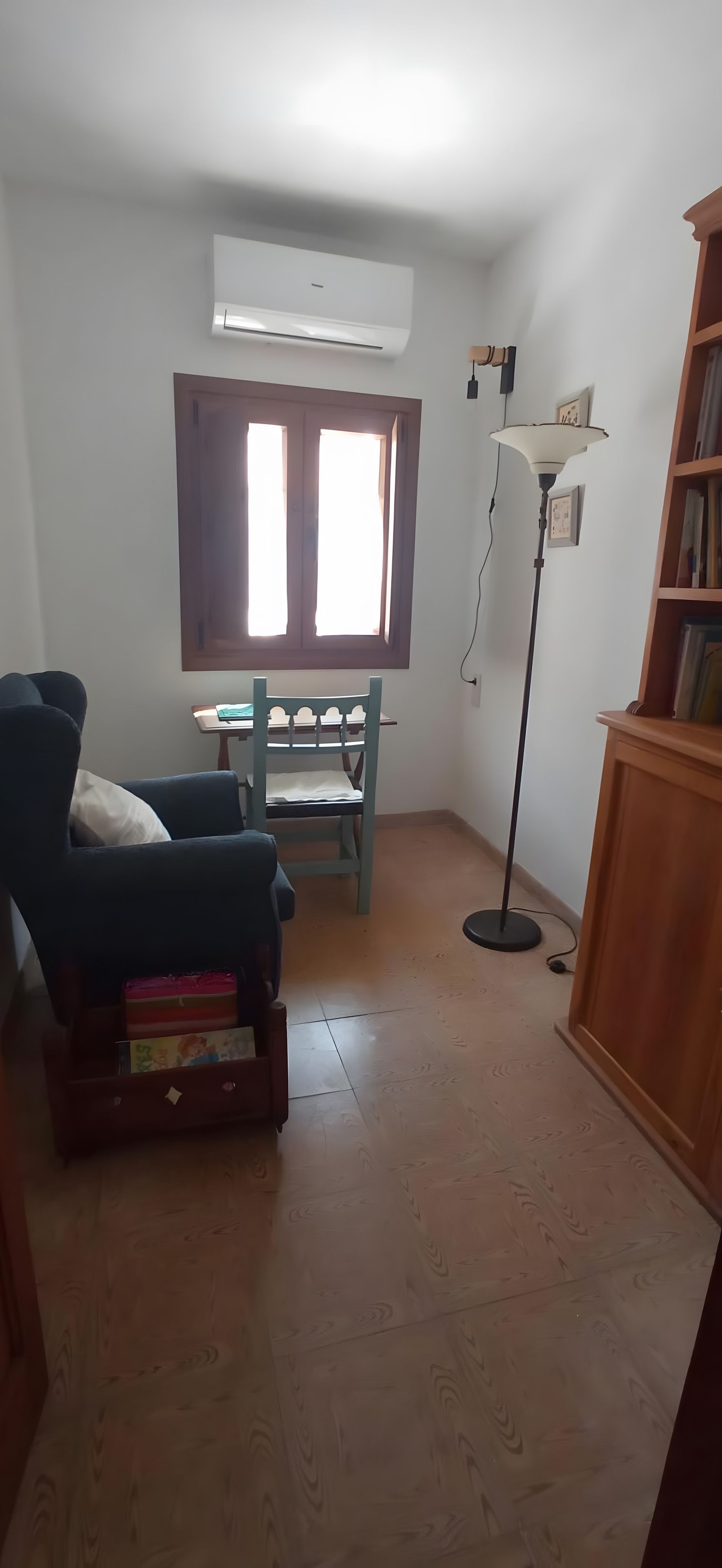 Een kamer met een stapelbed, een bureau, een stoel, een vloerlamp en een boekenkast.