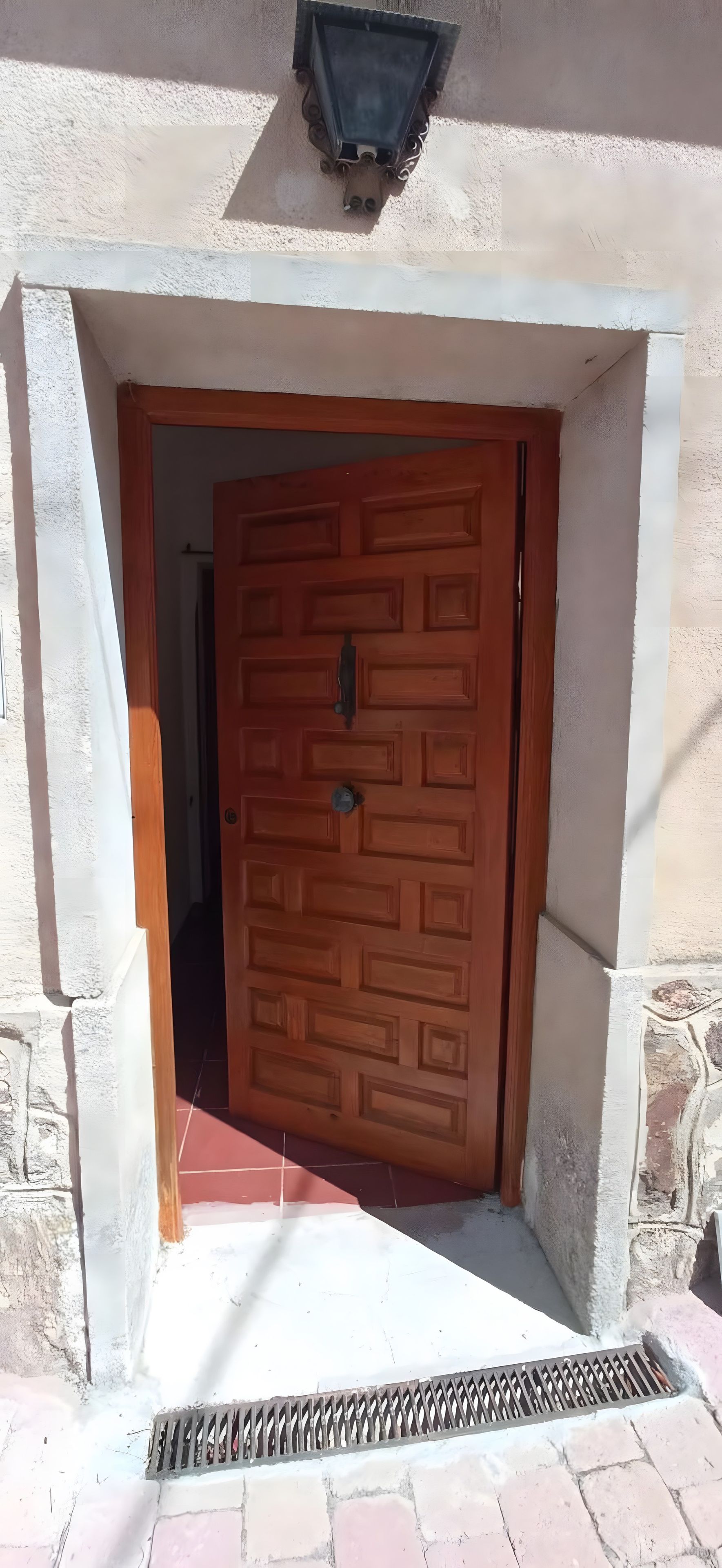 Une porte en bois ornée d’un motif géométrique, encadrée par un portail en pierre.