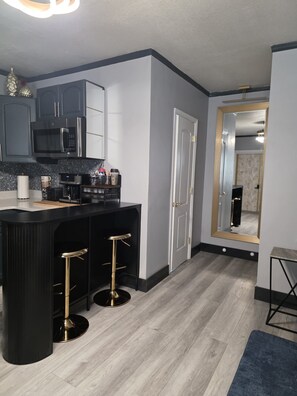 A modern kitchen with a black countertop, stainless steel appliances, and a bar area with stools. - Tranquil 1-bedroom apartment with AC in Orlando (Orlando)