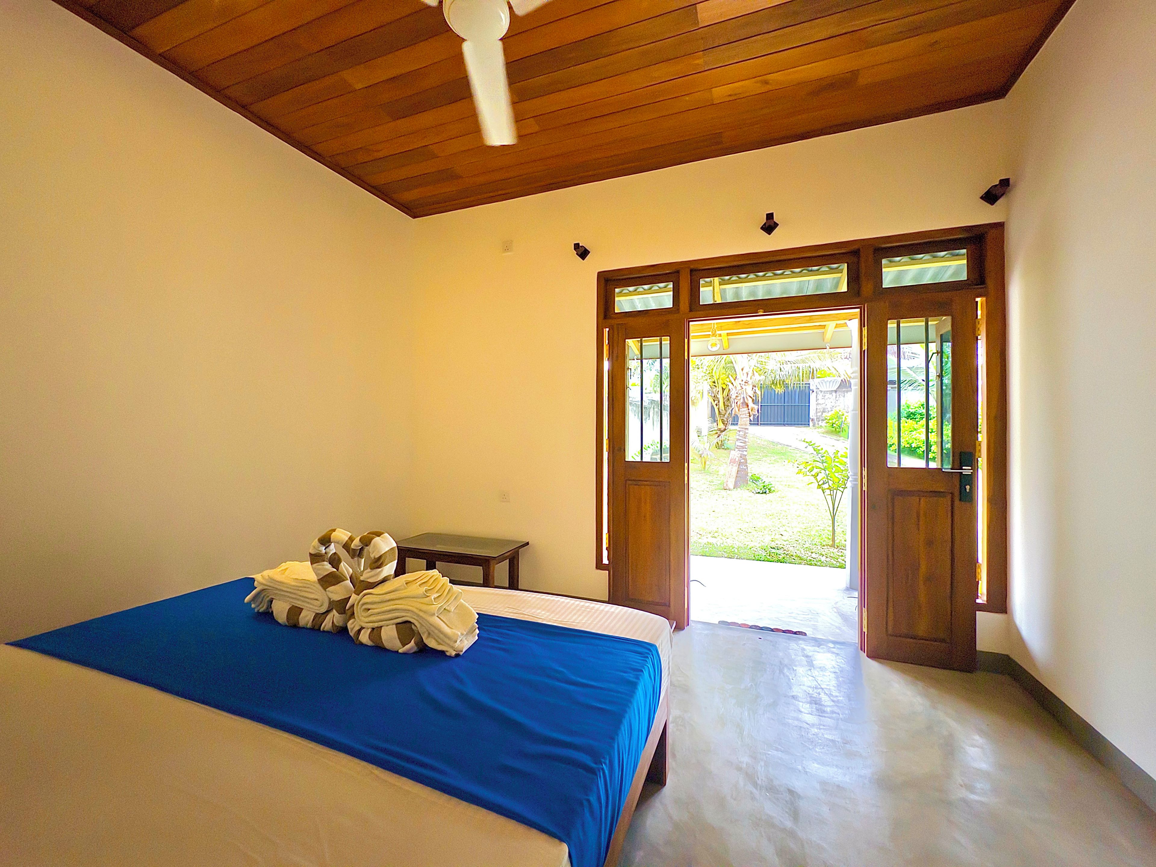 A bedroom with a bed, a wooden ceiling, and a door leading to a balcony.