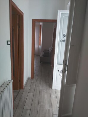 Ein Korridor mit Heizkörper, einer Couch und einer Tür mit einem Schild.