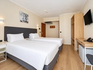 A hotel room with two beds, a desk, a television, and a painting on the wall. - Hotel Innova Milano Nord (Cinisello Balsamo)