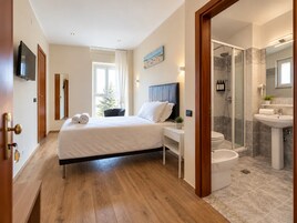 Habitación de hotel con cama, mesita de noche y zona de ducha.