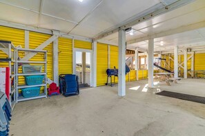 Een ruime binnenruimte met een gele muur, een betonnen vloer en een groot, open gedeelte met een houten constructie.