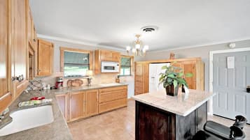 A kitchen with wooden cabinets, a granite countertop, a built-in microwave, and a chandelier.