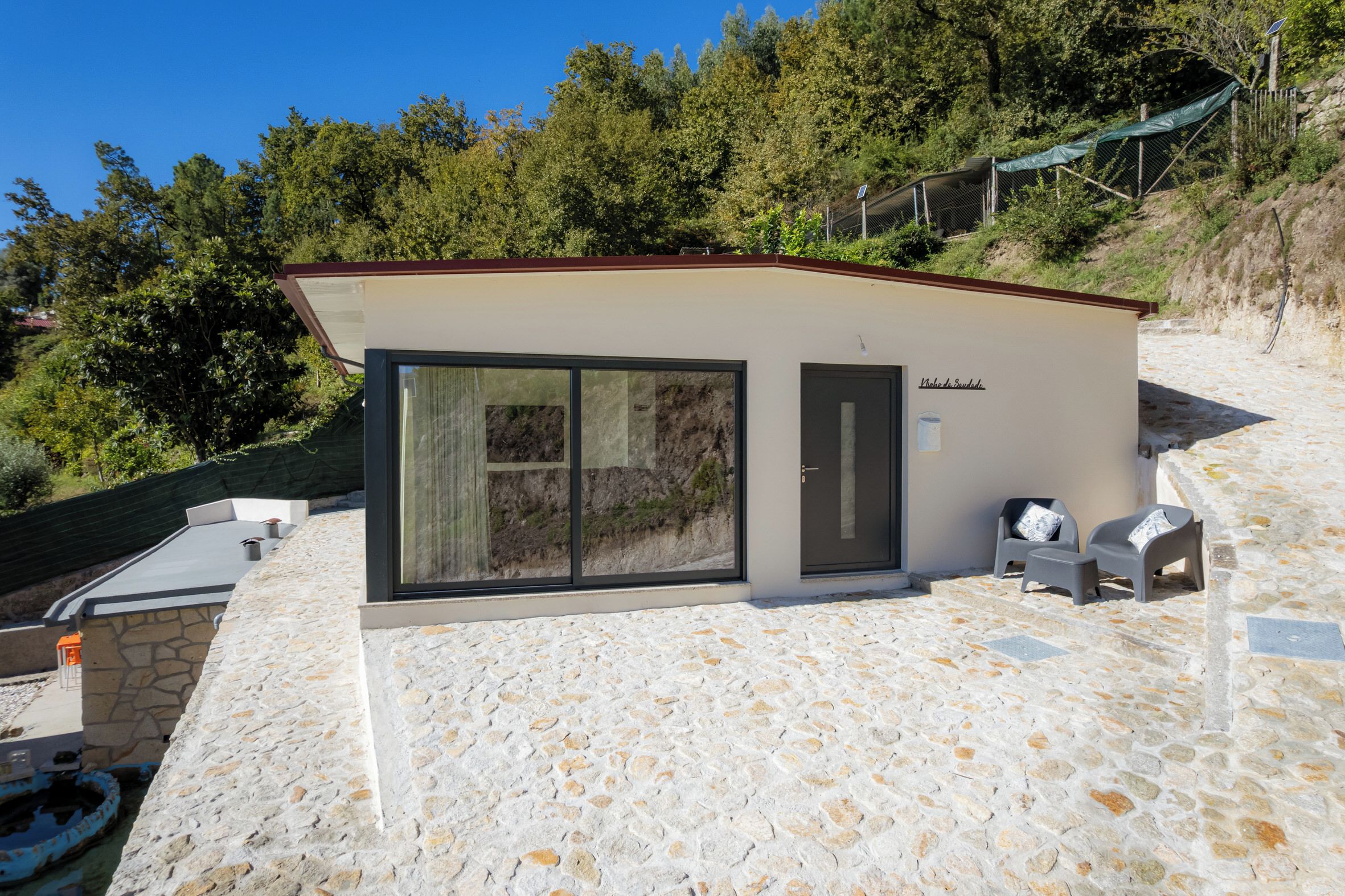 Un piccolo edificio moderno con facciata in pietra, ampie porte scorrevoli in vetro e tetto piatto.