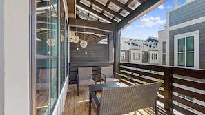 Un espace extérieur abrité, doté d’une table et de chaises, d’une terrasse en bois et offrant une vue sur les bâtiments voisins.