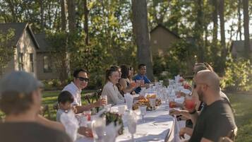 A group of people seated at a table outdoors with a house in the background.