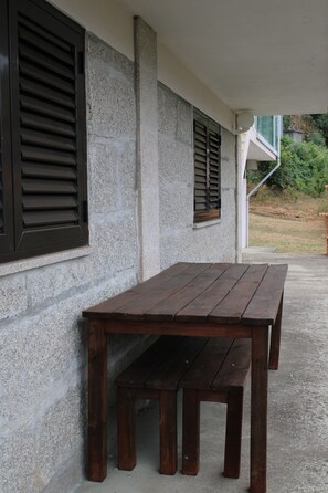 A wooden bench and table set against a stone wall with shutters. - Douro Nest House -  (Resende)