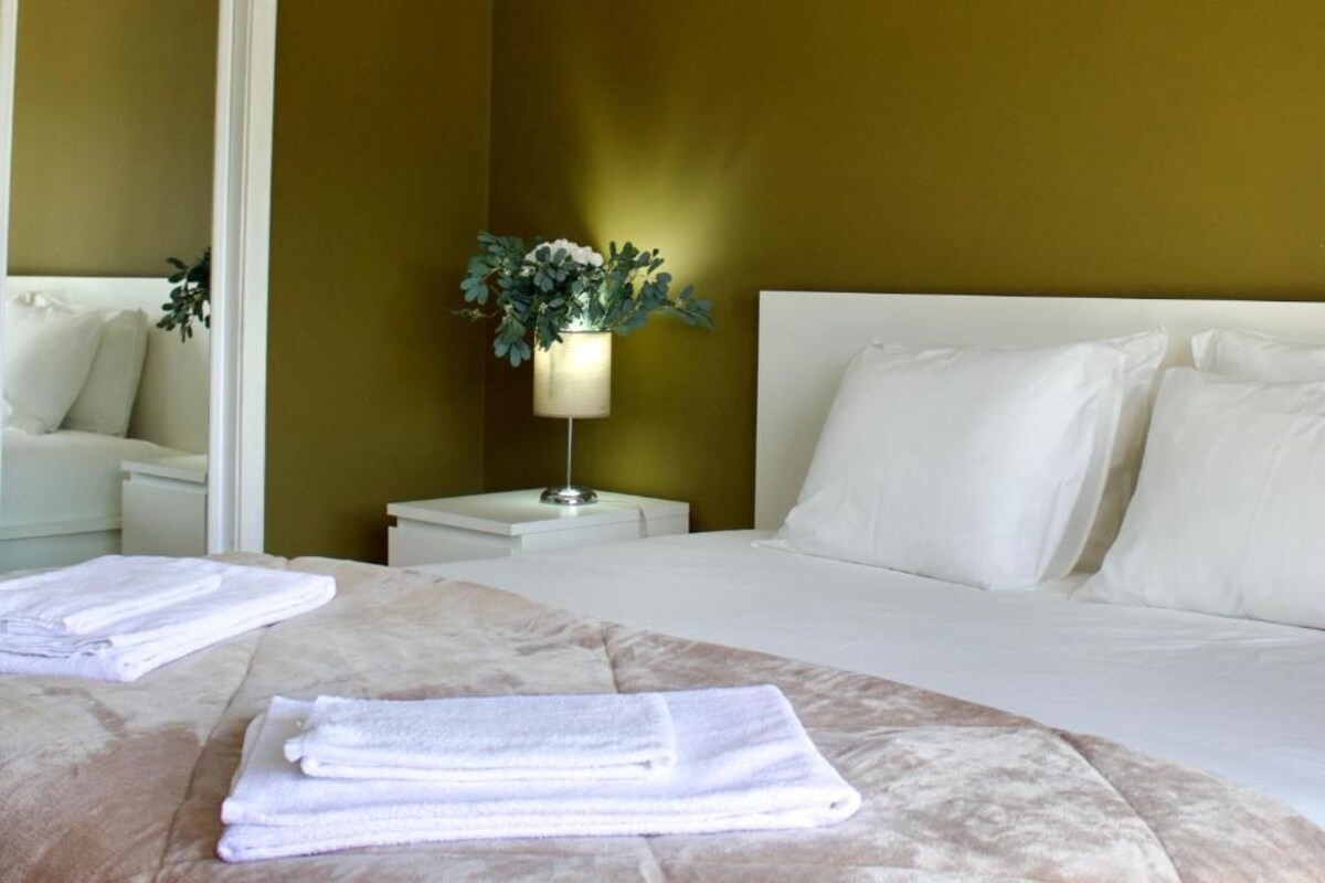 A hotel room with a bed, a nightstand, a lamp, and a wall-mounted plant.