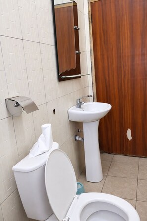 A bathroom with a toilet, sink, and wooden door.
