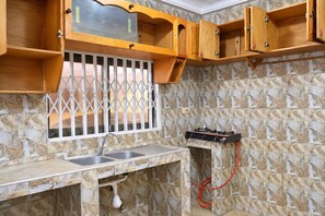 A kitchen with a marble backsplash, wooden cabinets, a double sink, and a gas stove.
