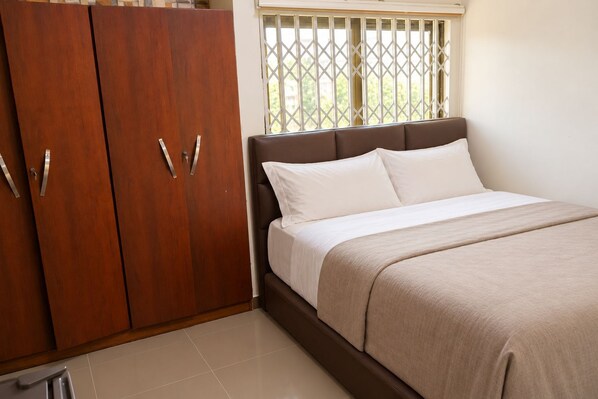 A bedroom with a bed, a wardrobe, and a window with a view.