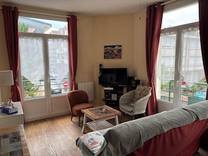 Una sala de estar con un sofá, un sillón, una mesita de centro, televisor y un cuadro en la pared.