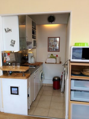Una cocina compacta con lavadora, microondas y un lavamanos pequeño.