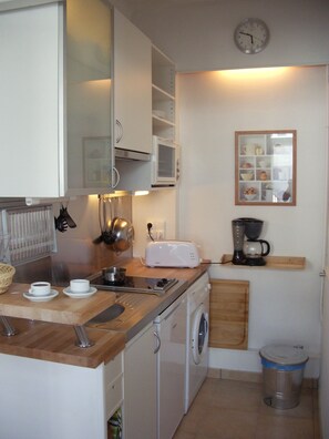 Cocina compacta equipada con microondas, tostadora, fregadero y lavadora.