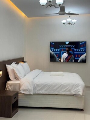Un dormitorio moderno con cama, mesita de noche y ventilador de techo.