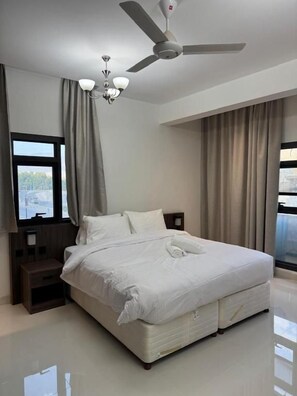 Un dormitorio moderno con una cama grande, un ventilador de techo y vistas por la ventana.