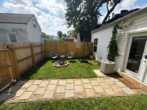 Un patio trasero con área de patio, cerca de madera y una casa blanca.