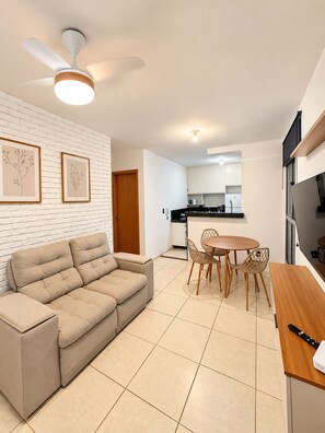 A modern living room with a beige sofa, a dining table with chairs, a ceiling fan, and a kitchen in the background. - New Listing (Lagoa Santa)