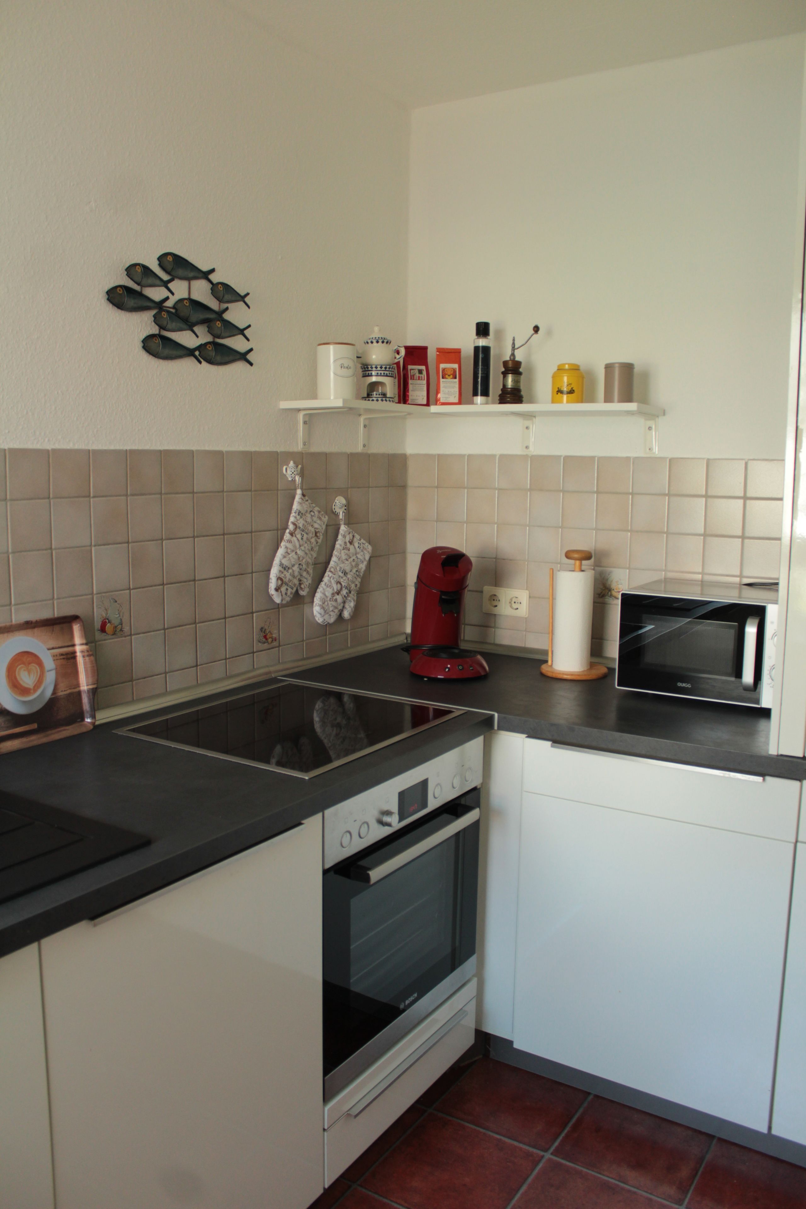 Eine Küche mit Herd, Backofen, Mikrowelle und einer Kaffeemaschine.