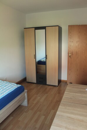 Une chambre à coucher avec une armoire, un lit et une porte.