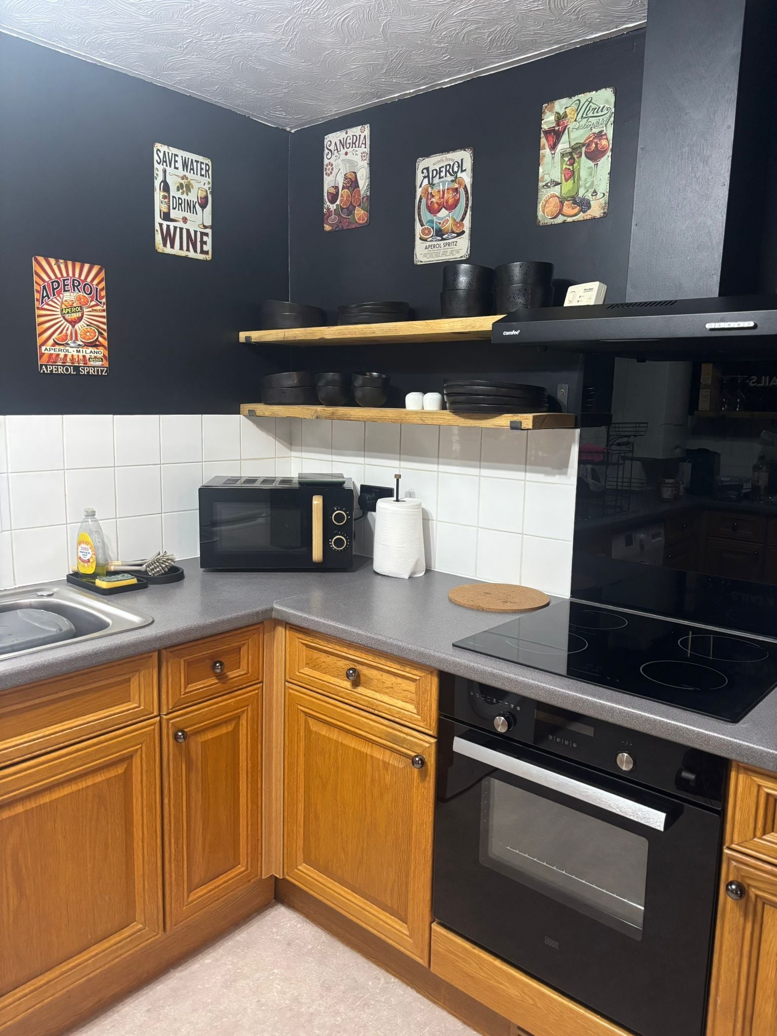 A kitchen with wooden cabinets, a microwave, a stove, and a coffee machine.