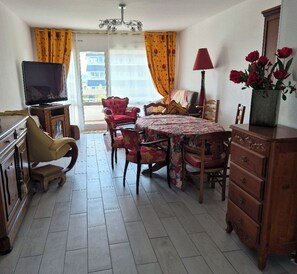 A dining area with a table, chairs, a television, and a dresser. - New Listing (Caen)