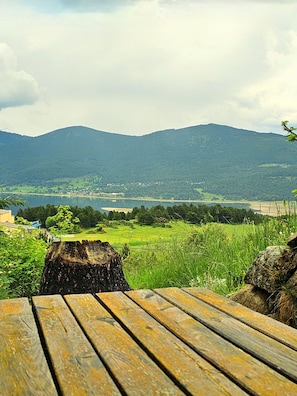 Ein Holztisch mit Blick auf einen See, Berge und ein Dorf in der Ferne.