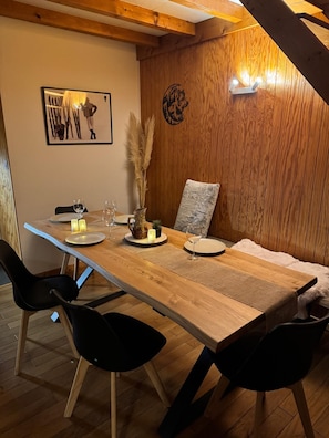 Ein Essbereich mit Holztisch, schwarzen Stühlen und einer wandmontierten Leuchte.